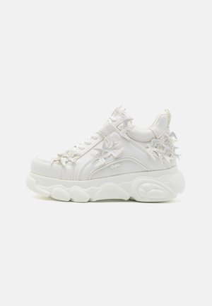 Biały masywny sneaker z grubą podeszwą i dekoracyjnymi akcentami w kształcie ptaków na bokach, pięcie i sznurowadłach na jednolitym tle.