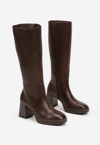 Bottes montantes en simili cuir marron avec des talons carrés, une texture lisse, des fermetures éclair sur le côté et un design à bout rond.