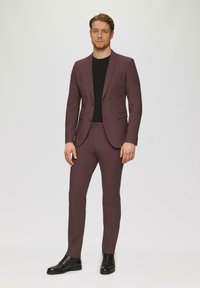 Tweedelig pak van diep bordeauxkleurige stof met een slim fit; enkelgeknoopte blazer, notch revers en voorzakken. Zwarte geklede schoenen.