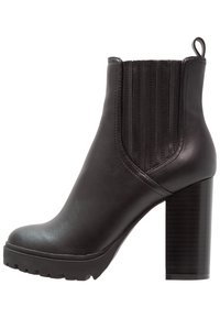 Czarne skórzane botki za kostkę z wysokim, wielowarstwowym obcasem, elastycznymi bocznymi panelami i teksturowanym wykończeniem na cholewce. Trwała gumowa podeszwa.