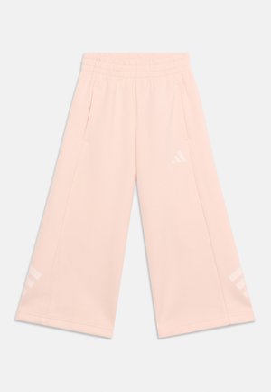 Svijetloroze široke hlače s elastičnim pojasom, bočnim džepovima i suptilnim bijelim Adidas logotipom na desnom bedrima i donjem dijelu lijeve nogavice.
