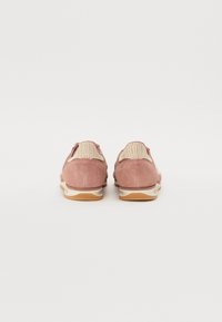 Pair of pink suede sneakers viewed from the back, featuring woven beige fabric on the heel and white rubber soles with light brown tread.