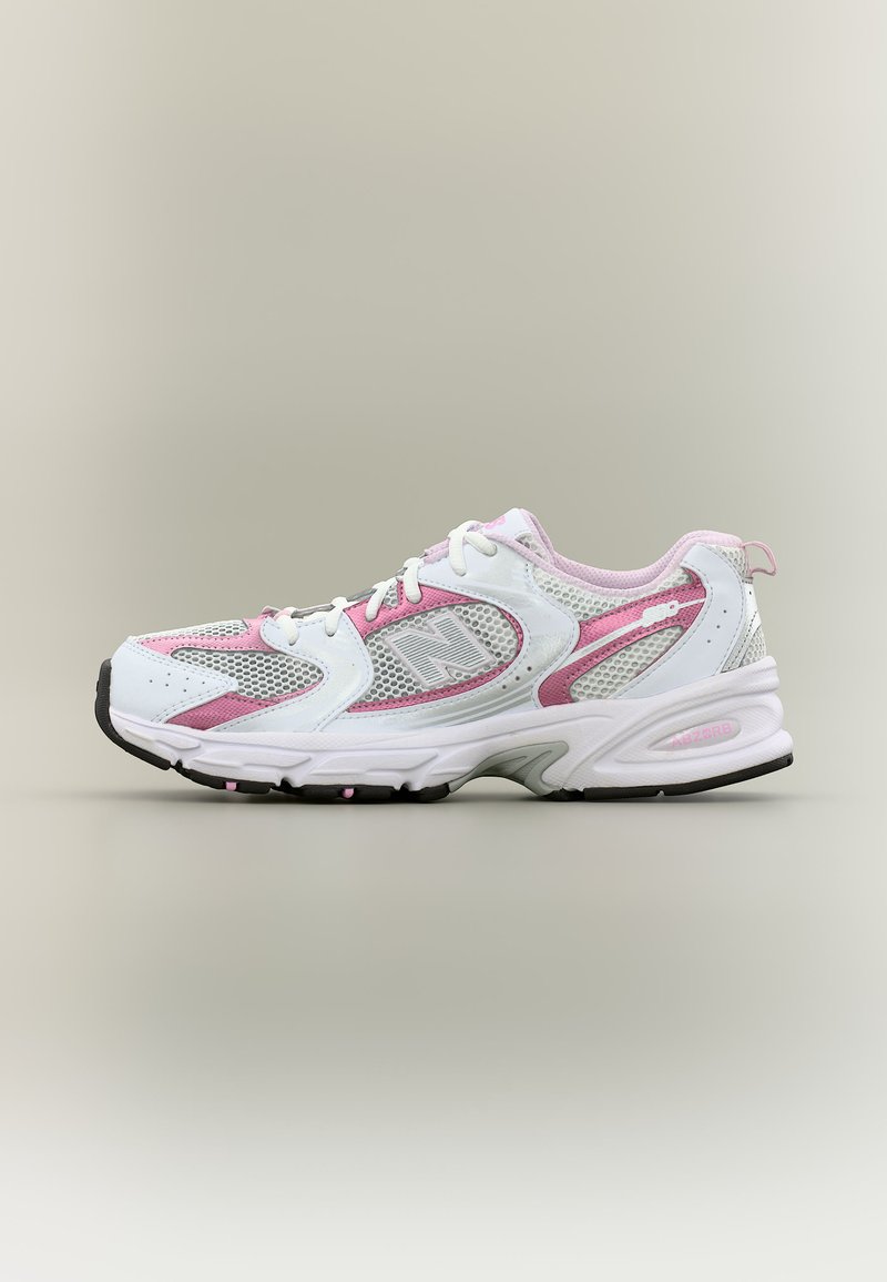 Baskets blanches et roses avec des panneaux en mesh, des lacets et une semelle épaisse, positionnées de profil sur un fond neutre.