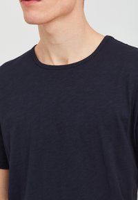 Tricou bleu marin din bumbac moale, cu guler rotund și maneci scurte, având o textură netedă și o finisare curată.