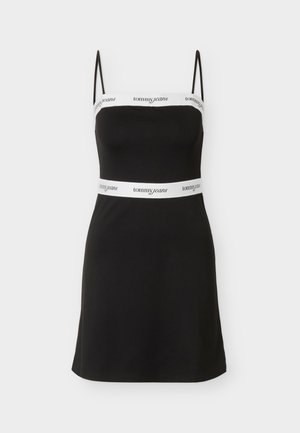 Robe mini noire sans manches avec fines bretelles, bandes blanches au niveau de la poitrine et de la taille arborant le logo "tommy jeans" en texte noir.