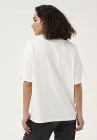 T-shirt bianco oversize in cotone morbido, con maniche corte, scollatura rotonda e vestibilità rilassata. Senza motivi o dettagli notevoli.