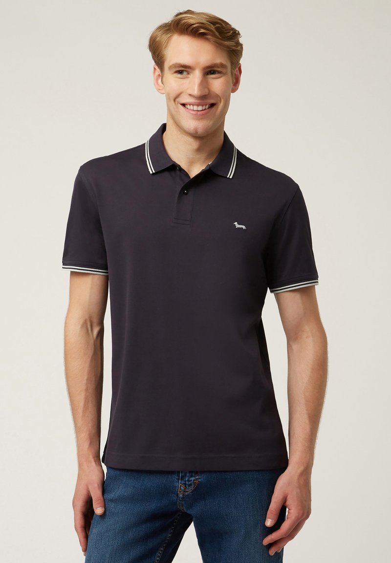 Polo shirt blu navy con colletto e polsini a righe bianche, realizzato in cotone testurizzato. Presenta un piccolo logo ricamato sul lato sinistro del petto.
