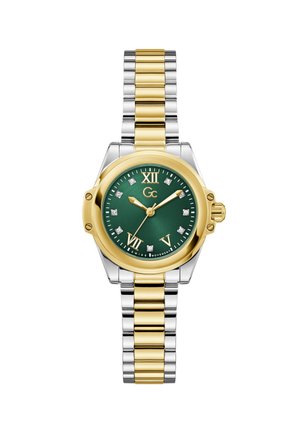 Kuldne ja hõbedane roostevabast terasest käekell rohelise sihverplaadiga, rooma numbrite, teemantaktsentide ja krooniga küljel. Linkidega käevõru disain.