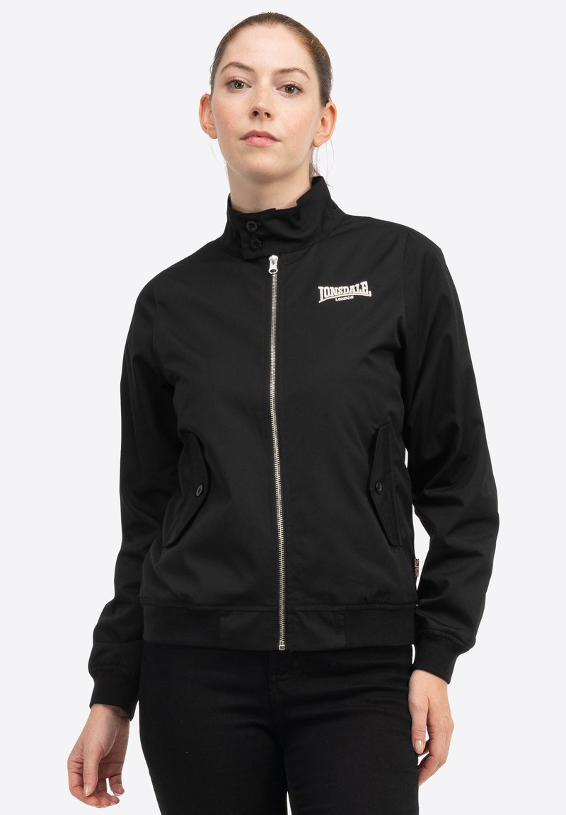 Veste bomber noire en tissu lisse ; dotée d'une fermeture éclair sur le devant, d'un col haut et de deux poches latérales avec fermetures à pression. Logo Lonsdale affiché.