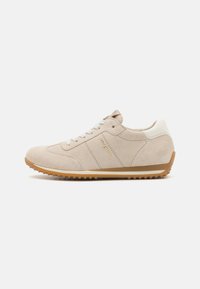 Beige semsket sneaker med rund tå, gummisåle og hvite accenter. Har teksturert overflate og kontrasterende sømdetaljer.