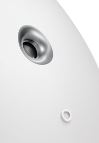 Haut-parleur sphérique blanc avec une grille métallique proéminente et un petit bouton circulaire blanc. Texture lisse et design minimaliste.
