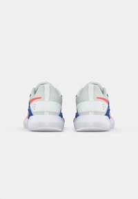 Ein Paar weiße, blaue und korallenfarbene Sportschuhe von hinten betrachtet, mit strukturierten Sohlen und Oberflächen aus Mesh auf einem schlichten Hintergrund.