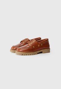 Brown leather boat shoes with lacing and gold eyelets, featuring a rubber outsole with ridges for grip and a reinforced toe.