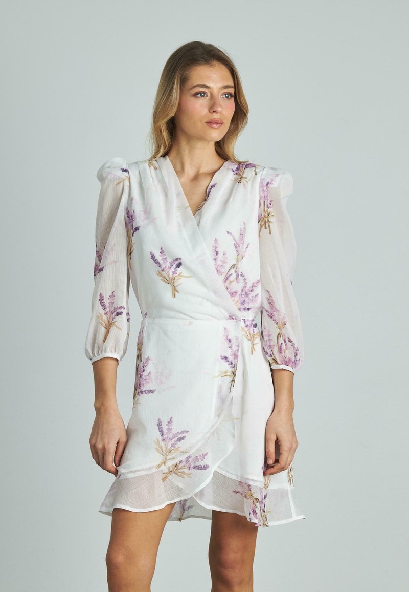Weißes Wickelkleid mit lila floralem Druck, durchsichtigen Dreiviertel-Puffärmeln, strukturiertem Stoff und einemRüschensaum.