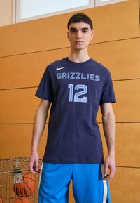 Mørkeblå sportstrøje med korte ærmer med "GRIZZLIES" og "12" i lyseblå. Båret med blå mesh shorts, som har et Nike-logo på brystet.
