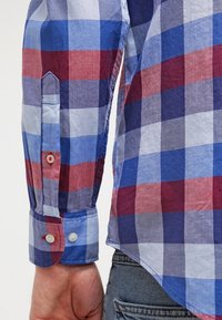 Baumwoll-Karohemd mit blauen, roten und weißen Quadraten, mit geknöpftem Manschettenverschluss und abgerundetem Saum. Glatte Textur und lockere Passform.