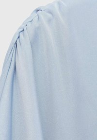Light blue fabric with a textured weave, featuring a gathered detail at the shoulder. Smooth surface, soft appearance, no visible patterns.