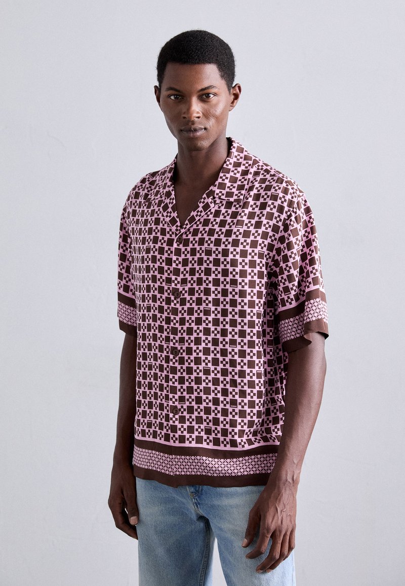Chemise à manches courtes à boutons avec un motif géométrique rose et marron, dotée d'un col cranté et de bandes d'accent en couleur unie aux poignets et à l'ourlet.