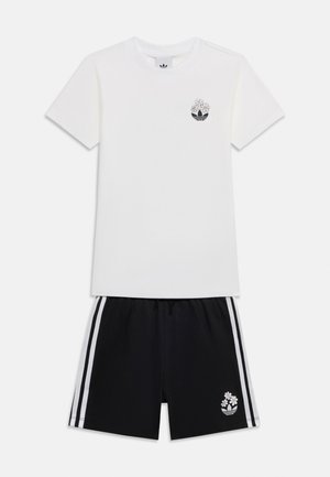 Tricou alb cu mâneci scurte și pantaloni scurți negri, ambele având un mic logo negru cu margarete și trei dungi albe pe lateralele pantalonilor scurți.