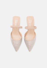 Ballerine nude a punta con applicazioni di strass luccicanti e un singolo elastico sulla parte superiore, esposte affiancate su uno sfondo bianco.