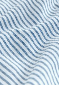 Pamuk tkanina s naizmjeničnim plavim i bijelim horizontalnim prugama, prikazujući meku teksturu i nježno padajući kroj.