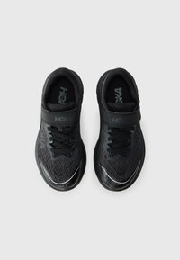 Chaussures de sport noires avec tige en maille, col rembourré et bande Velcro. Présente des lacets, un détail de logo et des accents réfléchissants. Design léger.