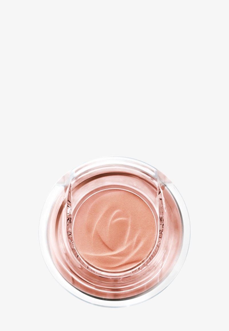 Contenant rond transparent avec une crème de maquillage couleur pêche embossée d'un motif de rose sur un fond blanc.