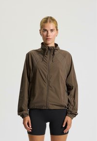 Bruine windbreaker jas met hoge kraag, ritsluiting en elastische manchetten. Lichtgewicht stof met een gladde textuur, ideaal om te lagen.