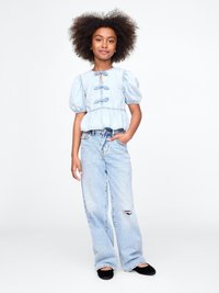 Lys blå denim-top med pufferm og knytedetalj ved halsen, kombinert med lys blå vide jeans som har en slitt detalj.