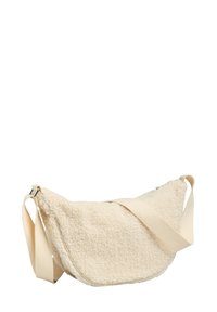 Bolso bandolera de color crema con forma curva, correa ajustable de lona y cierre de cremallera. Presenta material suave y texturizado de forro polar.