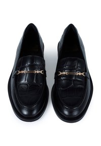 Black leather loafers with a textured crocodile pattern, featuring a gold-tone metallic accent across the upper. Flat soles, classic design.