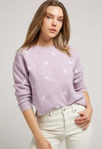 Pull en maille lavande clair avec broderies florales blanches, col rond et poignets côtelés. Assorti à un jean taille haute de couleur crème.