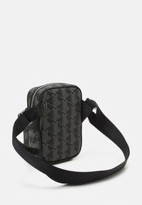Black patterned crossbody bag made of fabric, featuring a zip closure, adjustable strap, and geometric designs in light gray.