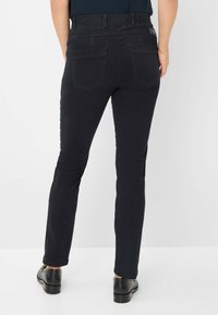 Jeans noirs stretch avec une taille haute, dotés de deux poches arrière, et au design slim-fit. Tissu lisse avec un léger éclat.