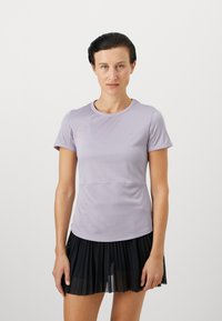Lys lilla kortermet treningsgenser med rund hals, i en tettsittende design, kombinert med et svart plissert skjørt for et sporty utseende.