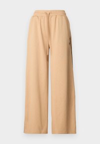 Pantalones anchos color beige con un patrón texturizado, cinturilla elástica, cordón y bolsillos laterales con acentos en negro.
