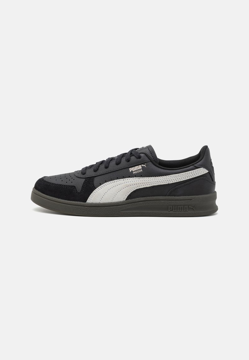 Sapatilha desportiva preta e cinza com um upper em camurça texturizada, detalhes perfurados e uma sola de borracha espessa com a marca PUMA.