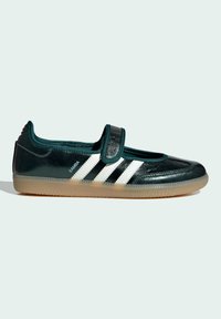 Dark green Adidas Samba shoe with white stripes, beige sole, and a Velcro strap across the top.