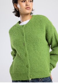Green knitted cardigan with a ribbed texture, round neckline, and five button closure. Long sleeves and casual fit.