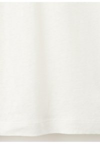 Tissu blanc uni avec des coutures visibles le long du bord inférieur, montrant les détails de la texture et du tissage.