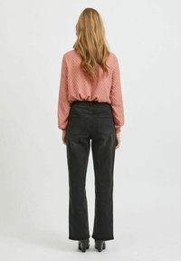 Blusa lunga a maniche con pattern zigzag testurizzato in rosa polveroso abbinata a jeans neri a vita alta e stivali neri con tacco a blocco.