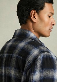 Flanellshirt mit einem schwarz-blauen Karomuster, aus strukturiertem Stoff, mit Kragen und einer klar definierten Silhouette.