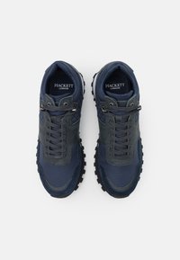 Baskets en mesh bleu marine avec accents en cuir, surfaces texturées, design à lacets et semelles en caoutchouc robustes. Logo présent sur la languette.