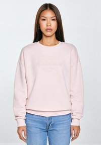 Jasnoróżowy sweatshirt z prążkowanymi mankietami i pasem. Posiada teksturowane logo "Authentic Big Star 1979" w jaśniejszym odcieniu. Luźny krój.