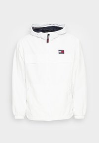 Biała lekka kurtka z kapturem ze ściągaczem, zamkiem błyskawicznym z przodu, elastycznymi mankietami i naszywką z logo na piersi. Materiał o fakturowanej powierzchni.