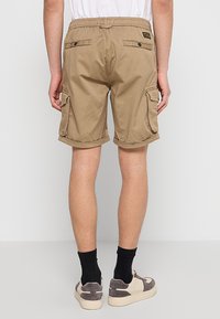 Khaki cargoshorts met een elastische tailleband, achterzakken met knopen en zijzakken. Opgerolde zoom en lichte stof.