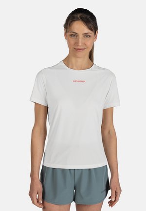 Weißes kurzärmliges Sportshirt mit Rundhalsausschnitt und rotem "ROSSIGNOL"-Logo, kombiniert mit grauen Shorts. Glatte Stoffstruktur.