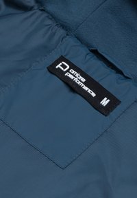 Tessuto blu navy con una texture liscia. Presenta un'etichetta con la scritta "ontheperformance" in testo bianco e la taglia 'M' su uno sfondo nero.