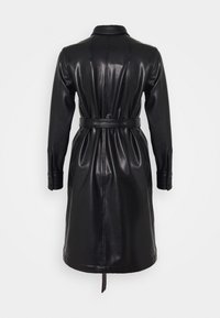 Černý kožený trenčkot s páskem v pase, dlouhými rukávy a knoflíkovými manžetami. Hladká textura a design po kolena s rozparkem na zadní straně.