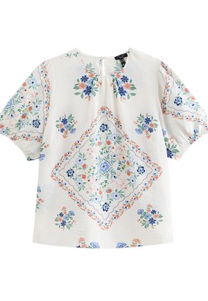 Blusa blanca de manga corta con mangas abullonadas y patrones florales multicolores dispuestos en forma de rombo en la parte delantera y las mangas.